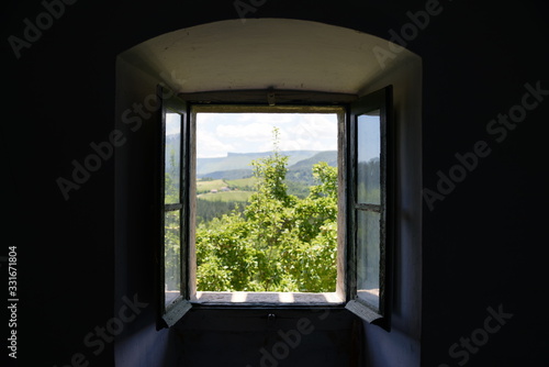 Vista de un paisaje campestre a trav  s de la ventana de una casa antigua