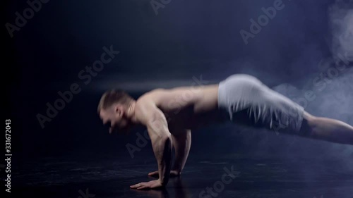 muscular man doing push ups on black with smoke