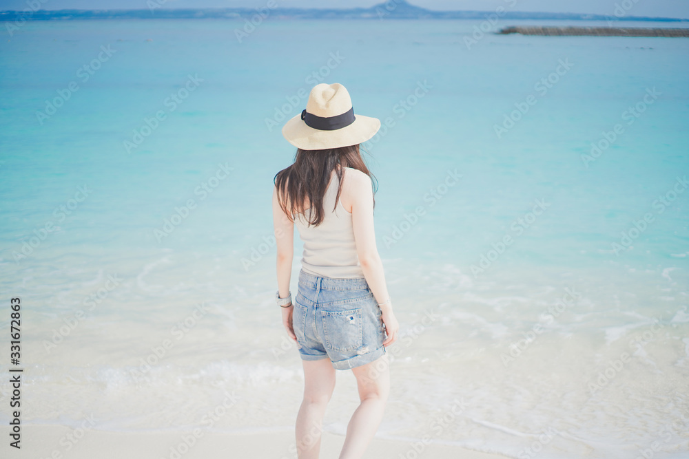 沖縄の海と麦わら帽子のロングヘアの女性