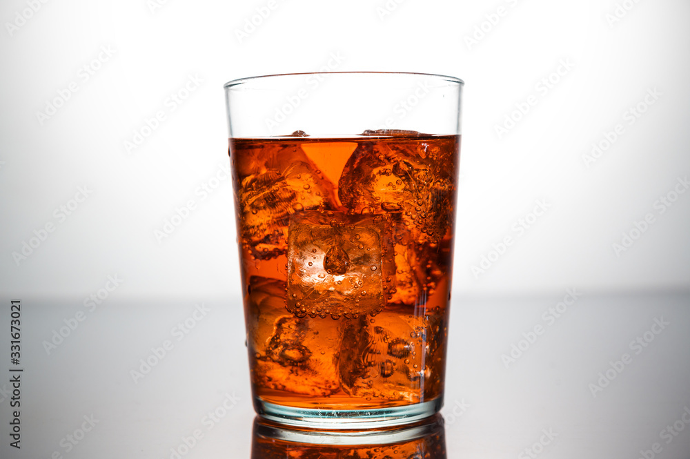 a glass of orange drink with ice cubes a glass of orange drink with ice cubes