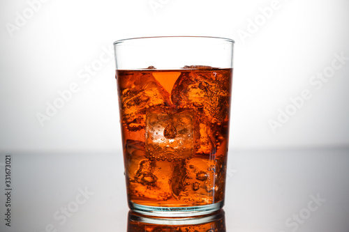 a glass of orange drink with ice cubes