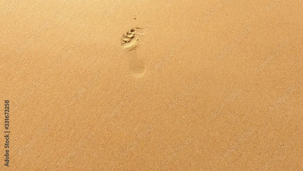 Lonely footprints in the sand on the beach are washed away by the sea wave Lonely footprints in the sand on the beach are washed away by the sea wave