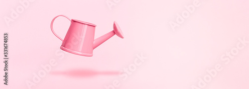 Quadro su tela levitating watering can on pink background, concept gardening accessories, panor