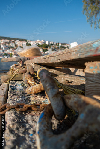 Samos island, pythagorion village with boats. Samos island. Greece. Sea and pythagorion village background. with collorful boats. in the front a big knot and chains
