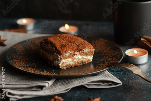 Tiramisu cake on a plate. Romantic composition with candles and other elements