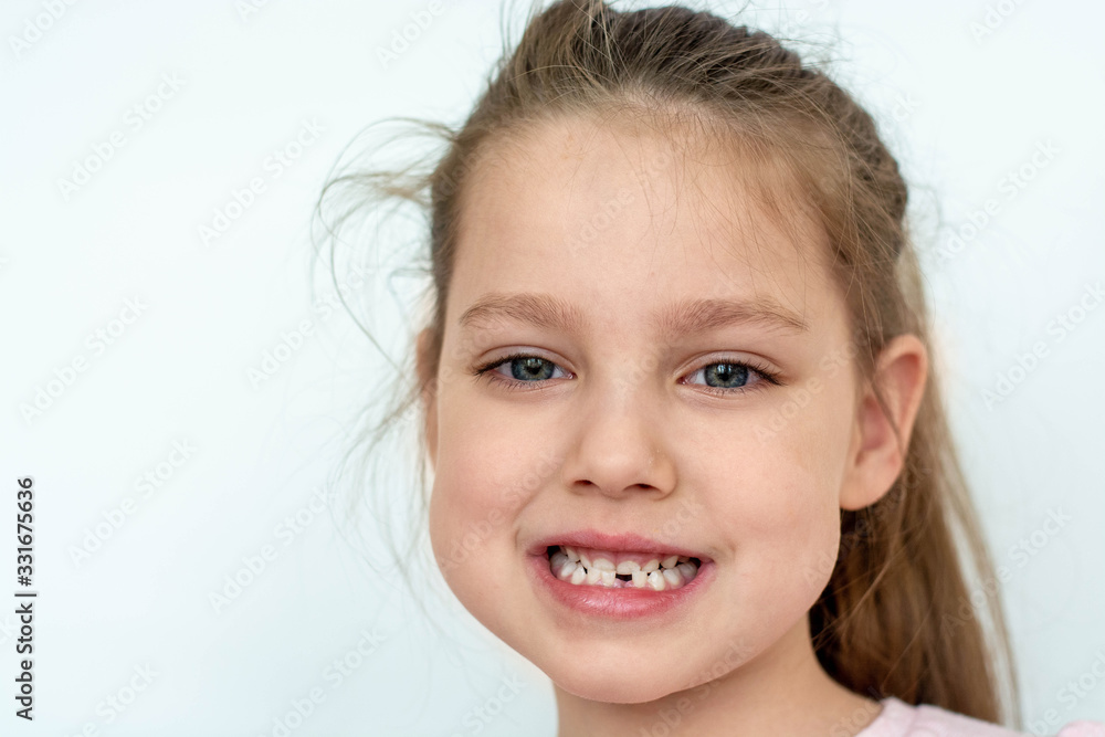 a happy girl in a pink school- age t-shirt without a front tooth laughs. To close. Diphyodont. Isolated on a white background. health a happy girl in a pink school- age t-shirt without a front tooth laughs. To close. Diphyodont. Isolated on a white background. health
