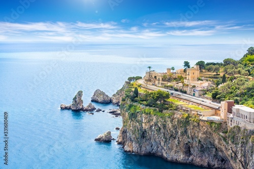 Blue sea and rocky coast at Cape Taormina. Taormina located in Metropolitan City of Messina, on east coast of island of Sicily, Italy.