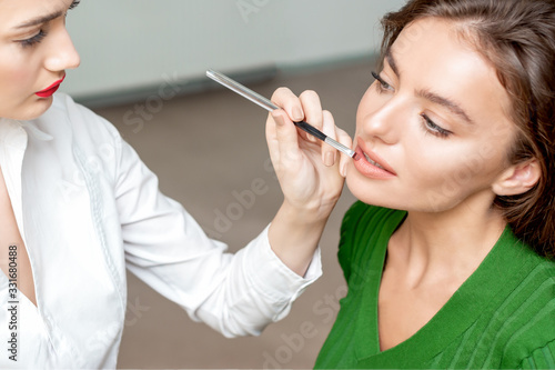 Makeup artist applies lipstick.