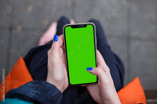 Woman wearing fashion clothes in dark blue and orange holding iPhone11 iPhone XR green screen, blue nails