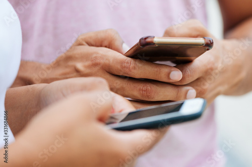 Cropped shot of young people using smartphones. Closeup shot of hands texting on modern phones. Technology concept