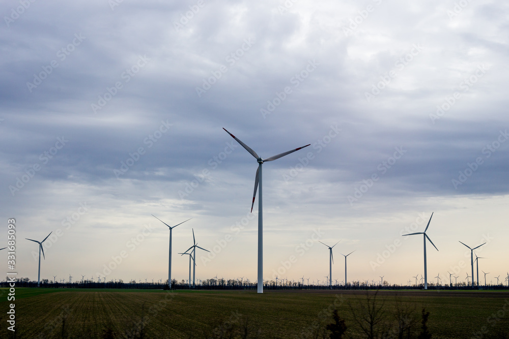 Modern windmills stand in a field against the sky Modern windmills stand in a field against the sky