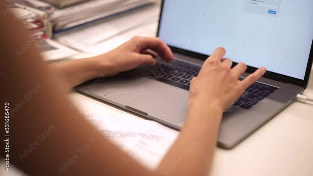 Podgorica, Montenegro - 10/13/2019: Side view of businesswoman's hands using laptop computer placed on messy office desktop. Work in office. Clerk, office worker. Co-working place. Close up shot. Podgorica, Montenegro - 10/13/2019: Side view of businesswoman's hands using laptop computer placed on messy office desktop. Work in office. Clerk, office worker. Co-working place. Close up shot.