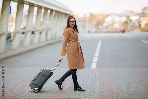 Full body side portrait of business woman walking with suitcase in terminal