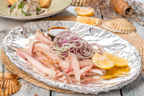 Fish slices with onion, sauce and lemon photo