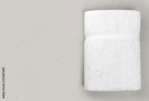 Obraz na plátně Top view of folded clean white bathroom towel on gray background with copy space