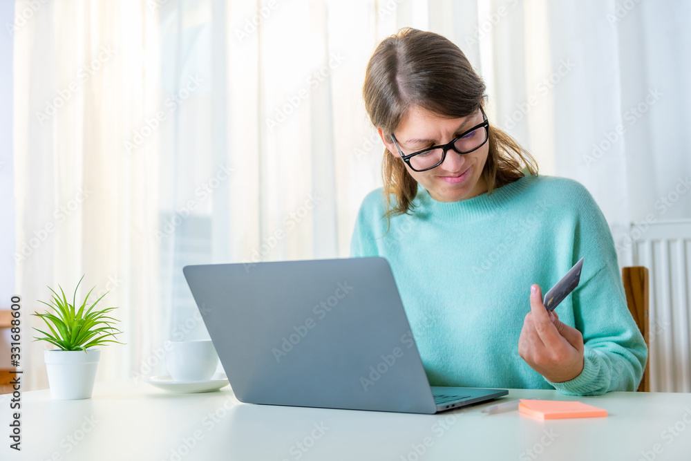 Young, modern smiling woman is looking at the data on her credit card at her home. Young, modern smiling woman is looking at the data on her credit card at her home.
