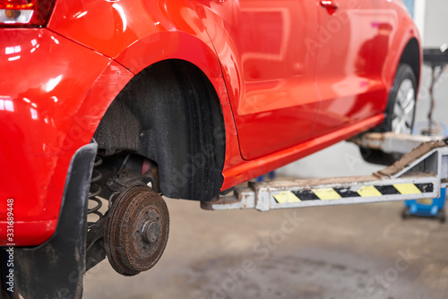 Rusty drum brakes, rear on red car. Change the old to new brake disc on car in a garage. Auto mechanic repairing