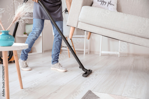 Young man hoovering floor u...