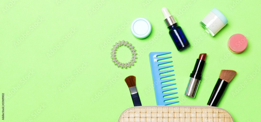 Aerial view of a leather cosmetics bag with make up beauty products spilling out on green background. Beautiful skin concept with copy space Aerial view of a leather cosmetics bag with make up beauty products spilling out on green background. Beautiful skin concept with copy space