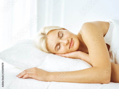 Beautiful young woman sleeping while lying in bed comfortably and blissfully. Good morning concept
