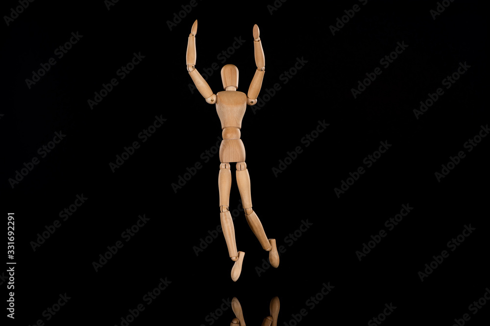 Wooden doll imitating dancing with outstretched hands on black Wooden doll imitating dancing with outstretched hands on black