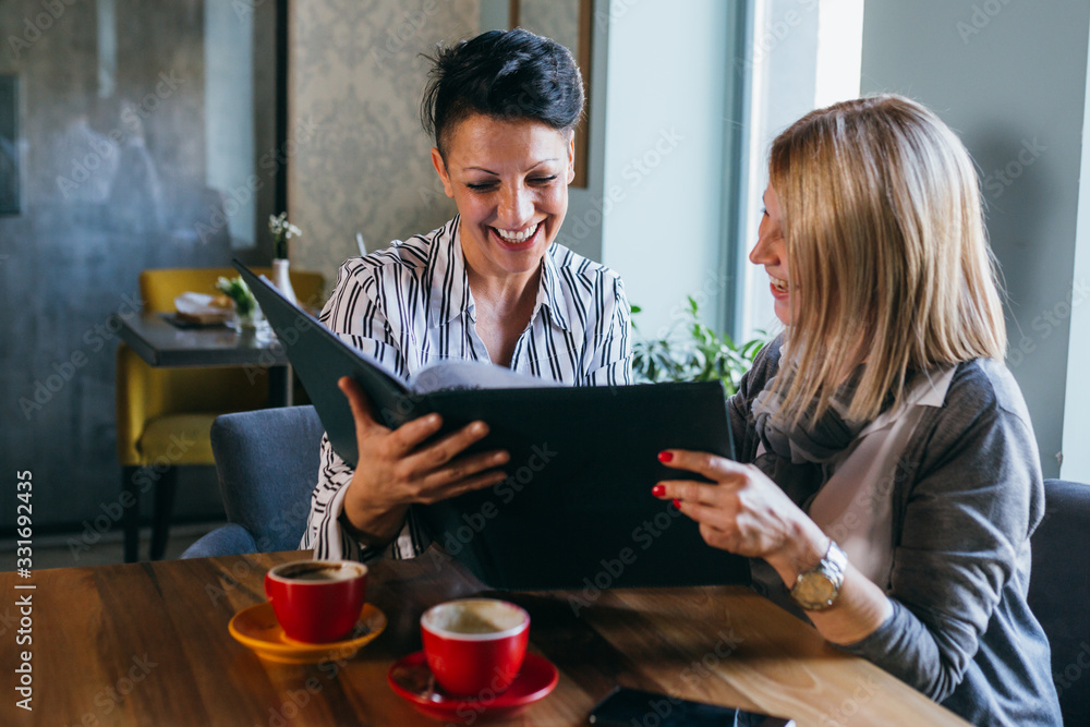women friends looking at the menu in restaurant women friends looking at the menu in restaurant