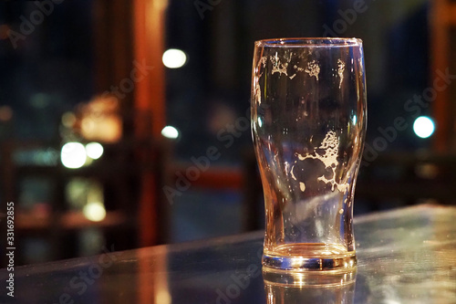 Empty beer glass on a table in a dark bar, pub