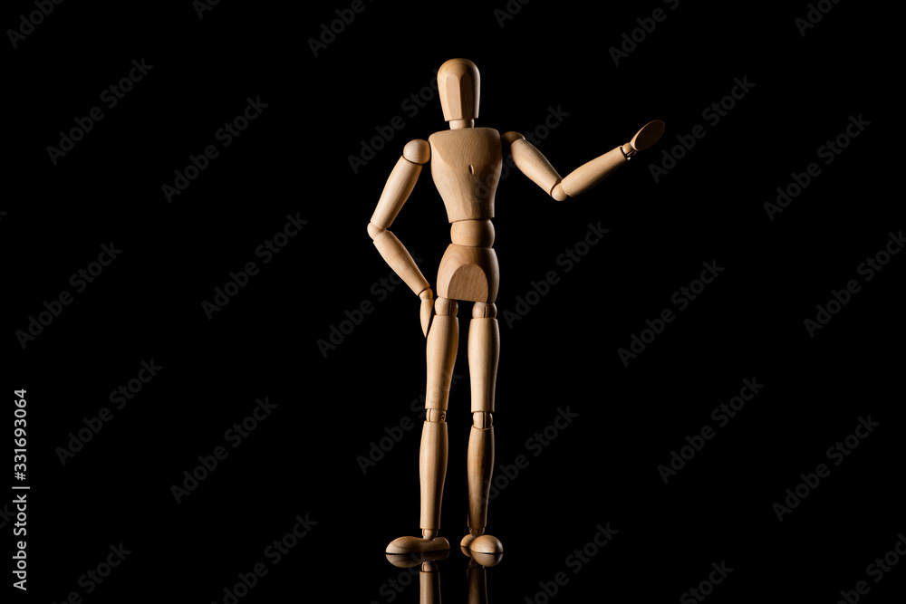 Wooden doll with hand on hip imitating pointing with hand on black background Wooden doll with hand on hip imitating pointing with hand on black background