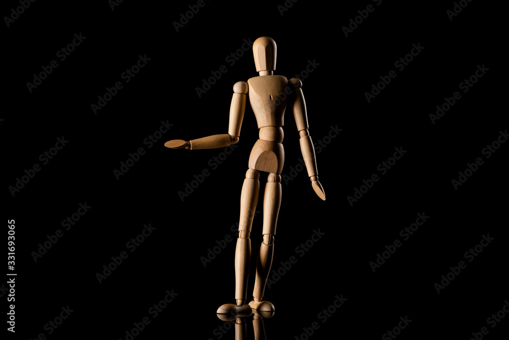 Wooden doll imitating pointing with hand on black background Wooden doll imitating pointing with hand on black background