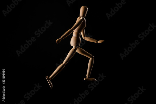 Wooden doll imitating running isolated on black