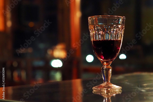 Glass of red wine on a table in a dark bar. Crystal glass with wine