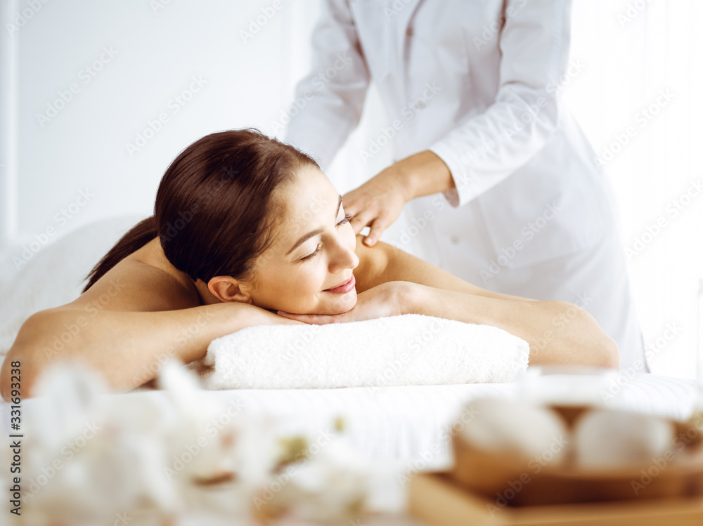 Beautiful brunette woman enjoying back massage with closed eyes. Spa and medicine concept Beautiful brunette woman enjoying back massage with closed eyes. Spa and medicine concept