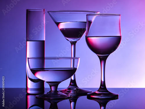 Different glass goblets on a and purple background. Beautiful still life