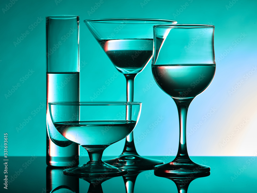 Different glass goblets on a turquoise background. Beautiful still life Different glass goblets on a turquoise background. Beautiful still life