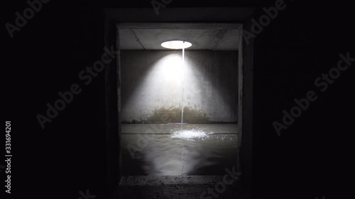Little waterfall in underground sewer square tunnel.
