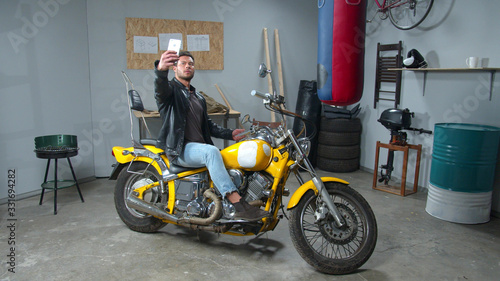 Man in leather jacket makes photo with a motorcycle 