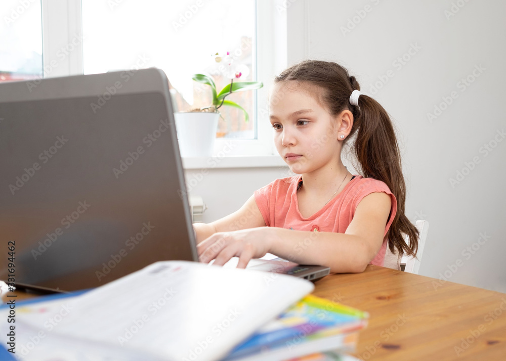 Caucasian preteen girl concentrated on her task with laptop. Concept of distance learning in isolation while coronavirus Caucasian preteen girl concentrated on her task with laptop. Concept of distance learning in isolation while coronavirus