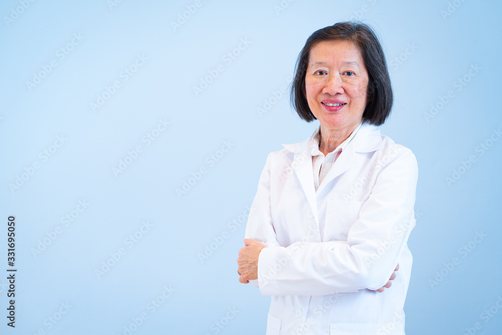 An old asian woman doctor is smiling and wearing white gown on the blue background An old asian woman doctor is smiling and wearing white gown on the blue background