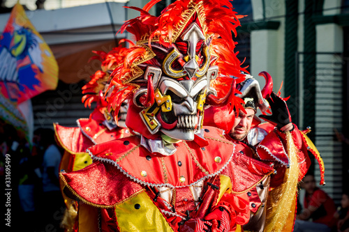 closeup people in flamboyant costumes pass by city street at dominican carnival
