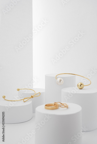 Golden Modern bracelets on white paper platforms