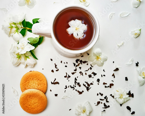 Tea cup with Jasmine flowers and cookies on white background