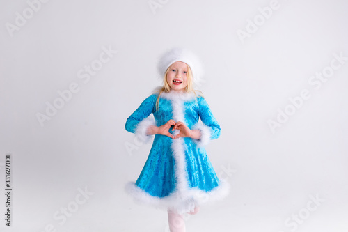 Little blonde girl in a christmas and new year Santa costume having fun and sending kisses on red background. Space for text. Dreams come true Merry Christmas