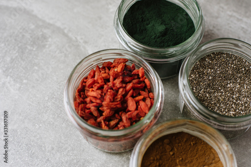 Selection of healthy nutritious superfoods for a healthy lifestyle. Dried goji berries, chia seeds, spirulina, carob in a close up view