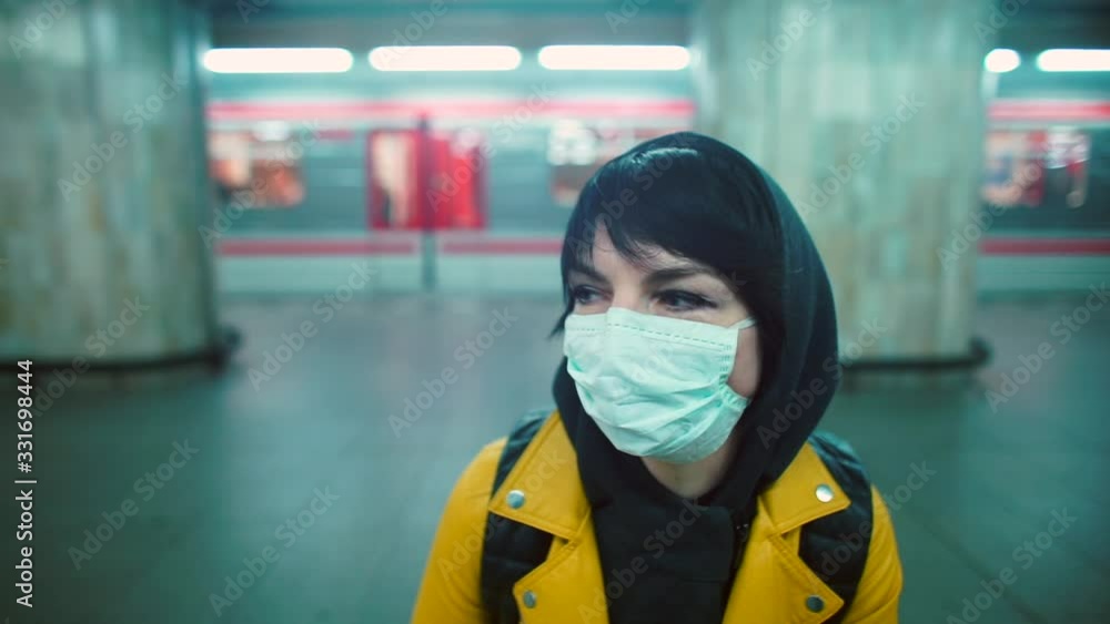 Female volunteer in medical mask is talking cell phone in subway. Potential transmission sites of coronavirus. SARS-CoV-2 pandemic in Europe. Quarantine. Female volunteer in medical mask is talking cell phone in subway. Potential transmission sites of coronavirus. SARS-CoV-2 pandemic in Europe. Quarantine.