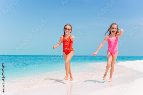 Little happy funny girls have a lot of fun at tropical beach playing together. © travnikovstudio