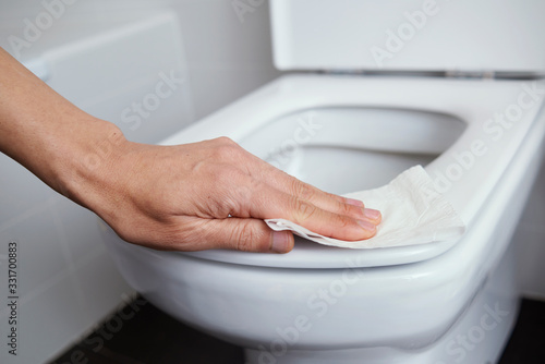 man cleaning the toilet seat with a piece of paper photo