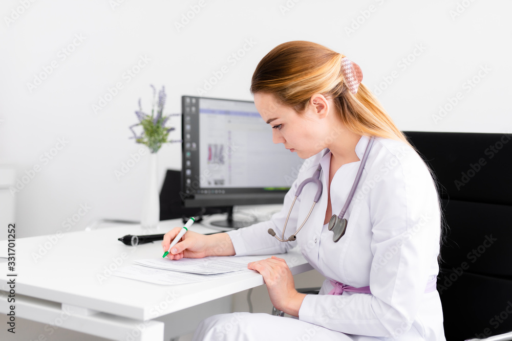 Young blonde doctor working on computer in new clinic. Helthcare concept Young blonde doctor working on computer in new clinic. Helthcare concept