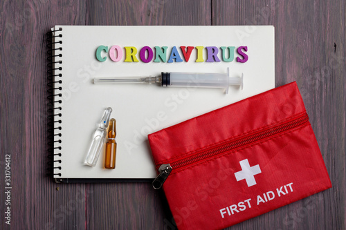 Text Coronavirus wooden letters on notebook and first aid kit on wooden background