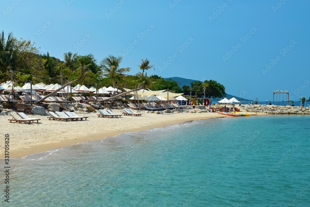 Sunbeds and umbrellas on a sandy beach with blue water in the tropics