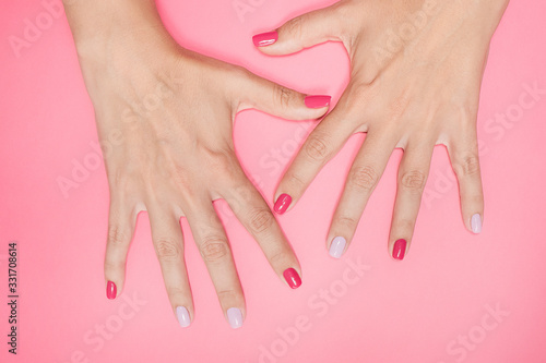 Closeup top view flatlay photography of two beautiful stylish manicured female open hands gesture with all fingers up isolated on pastel pink background.